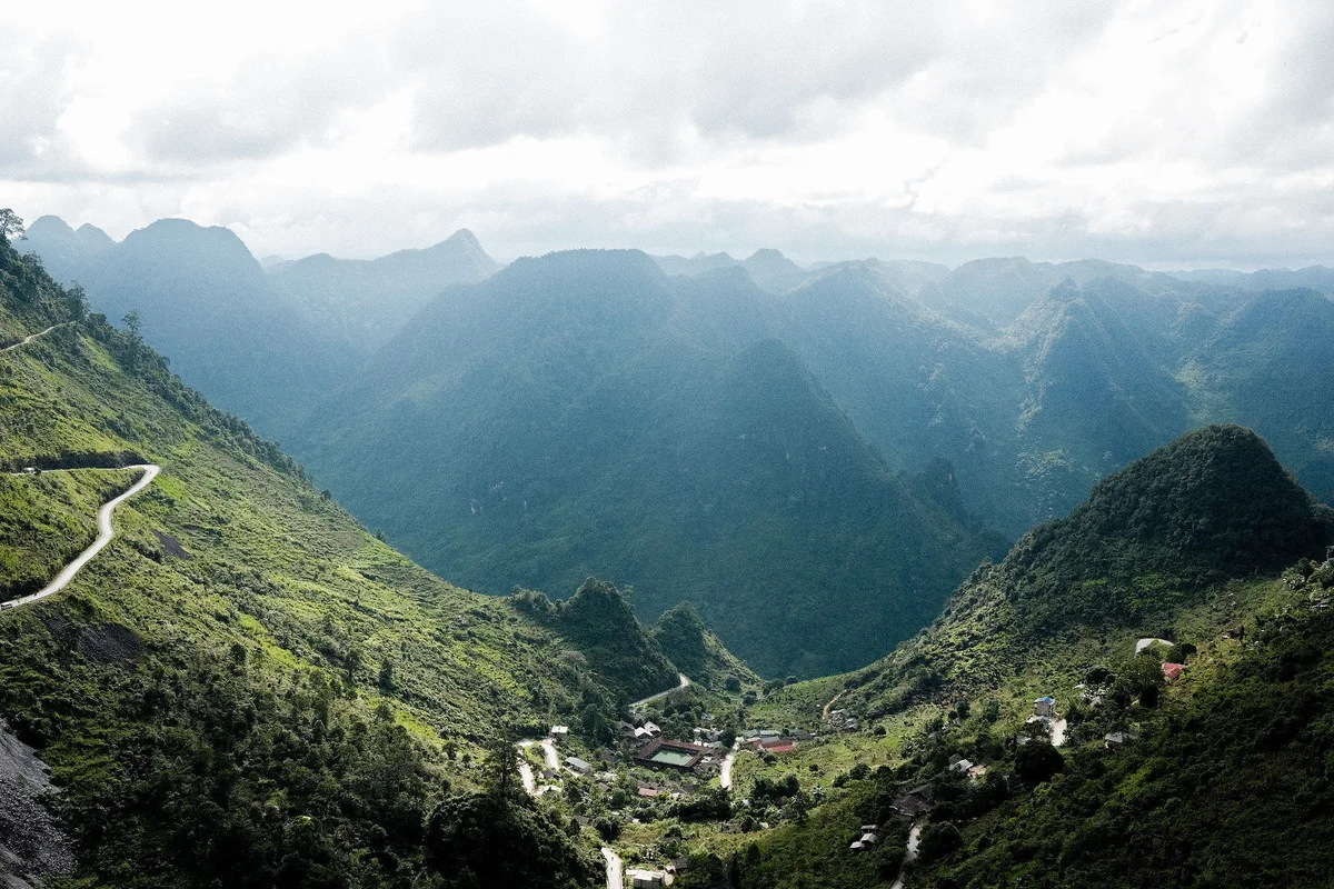 Village nestled in a valley with mountains around and sun shining down