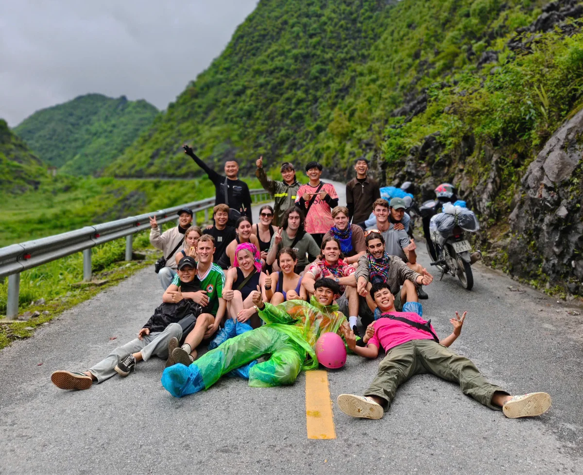 A group of people lie in the road posing for a picture together