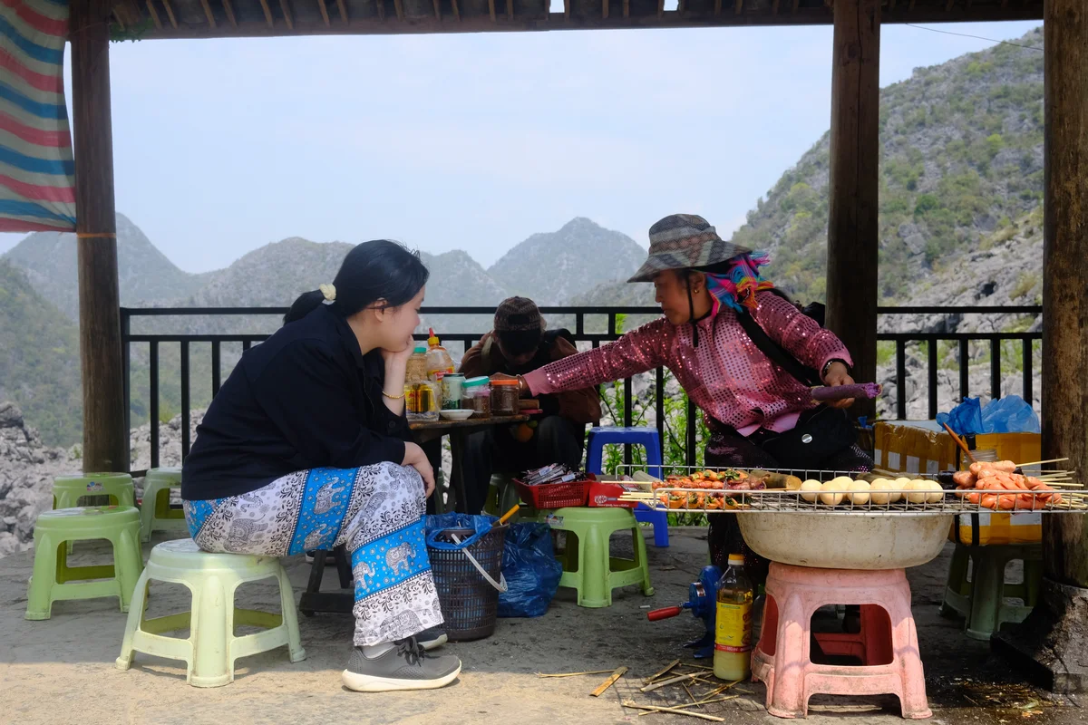 Woman waits for food from a vendor on the Ha Giang Loop