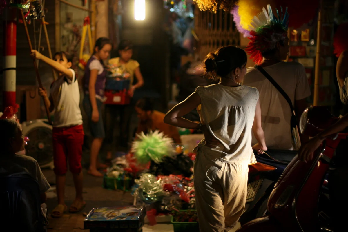 Woman standing at a market in dimly lit street of Hanoi