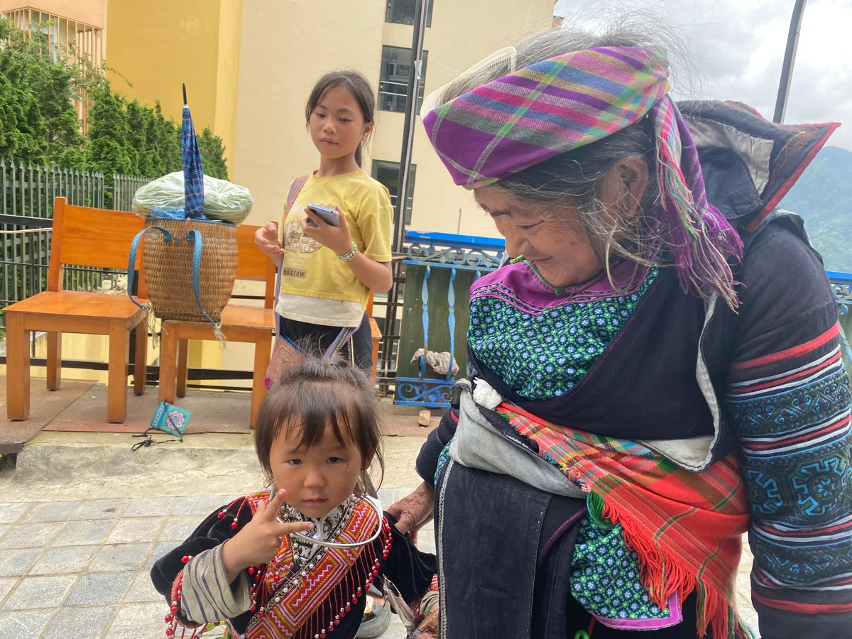 A small girl makes the peace sign to the camera while her grandmother smiles