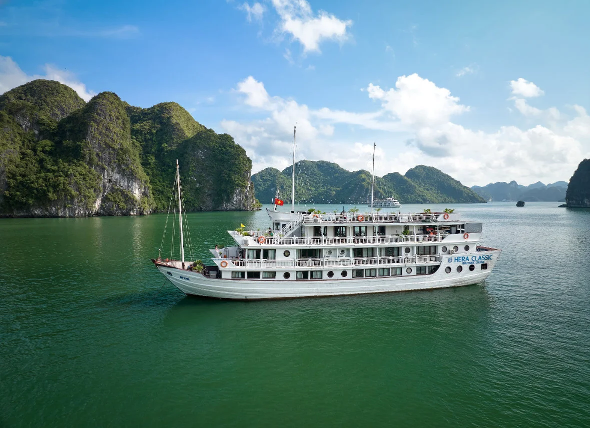 Cruise ship on emerald green waters with mountain backdrop