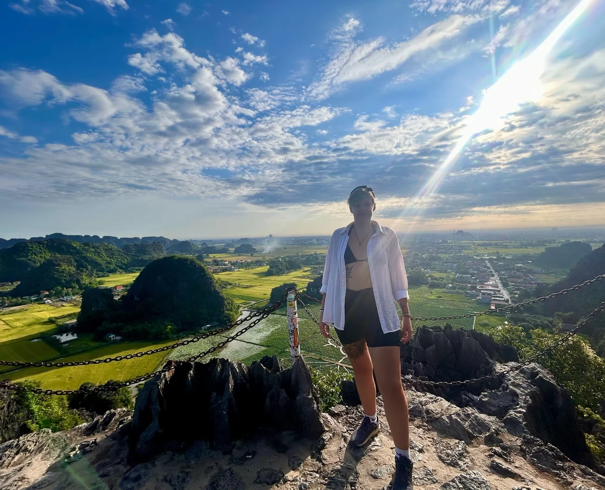 Woman standing at the top of a viewpoint with landscape stretching out below