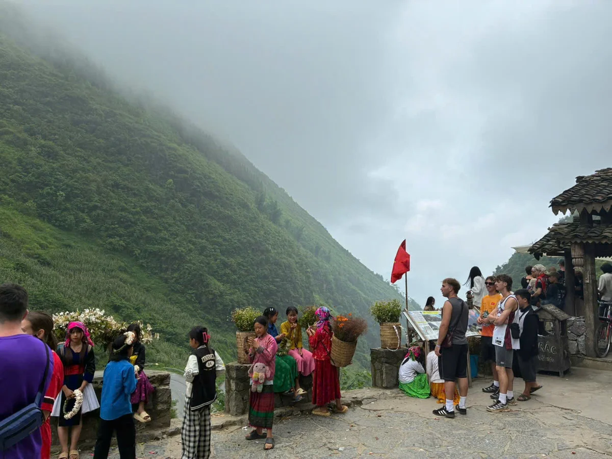 People stand around at a mountain pass viewpoint with mist hanging 