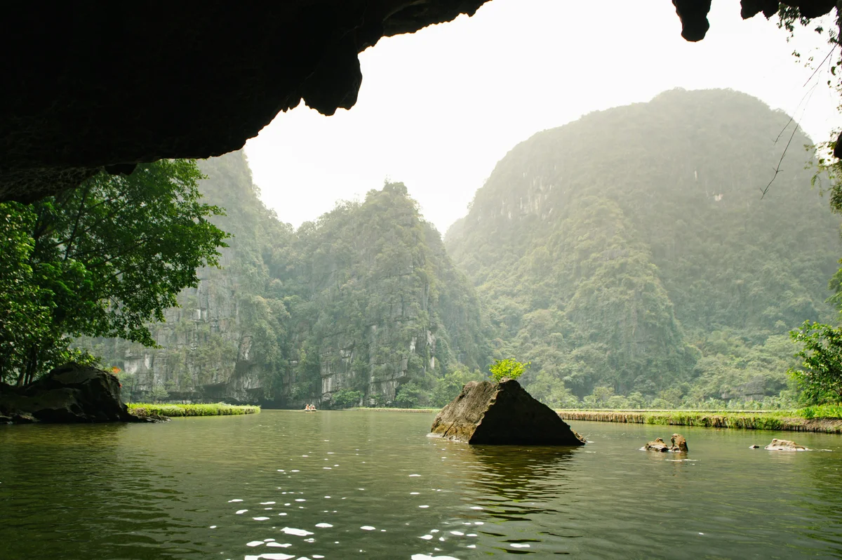 Mountains and rocks on the water with a cave entrance overhanging the image