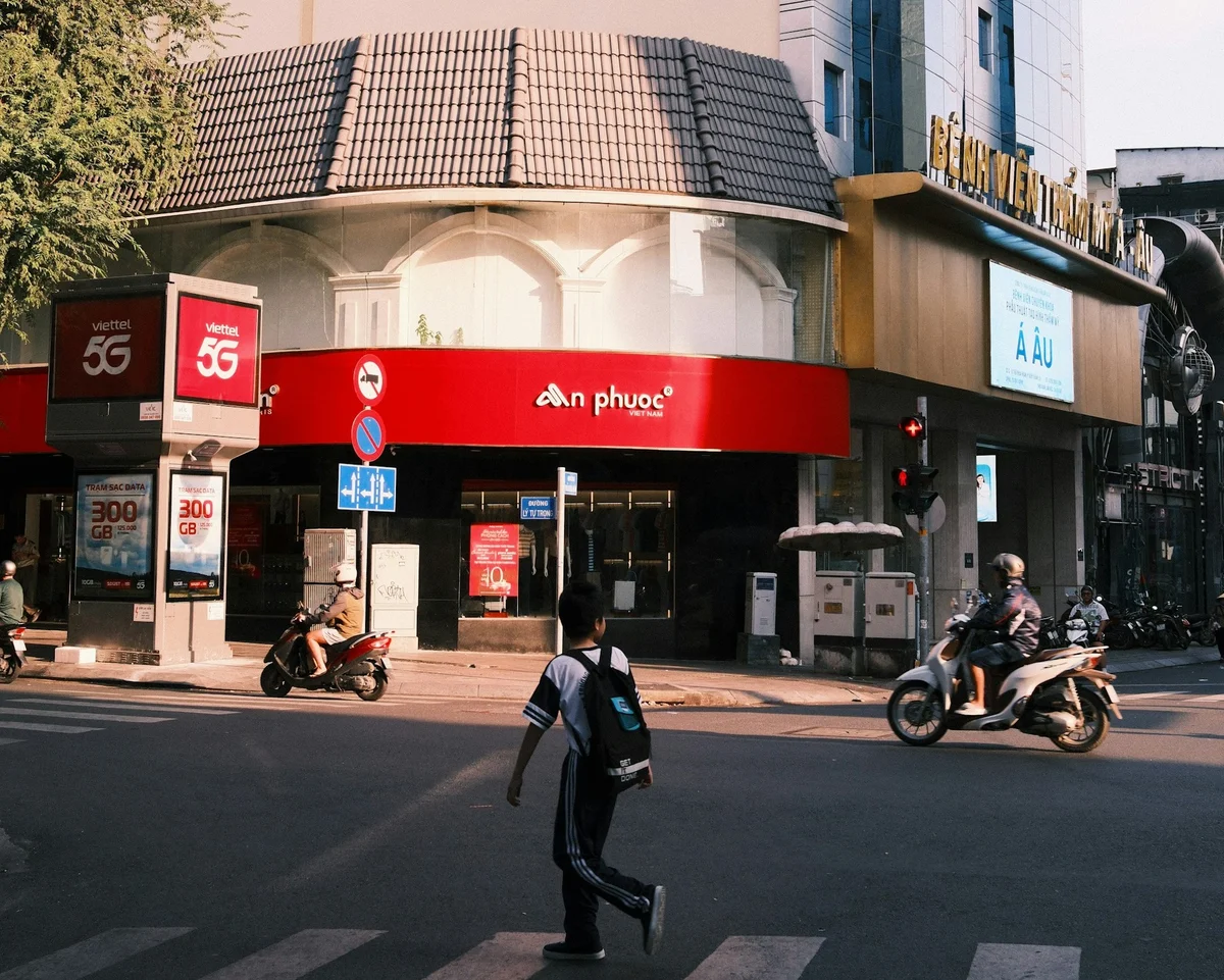 A phone store on a street with a sign nearby that says 'Viettel 5G'