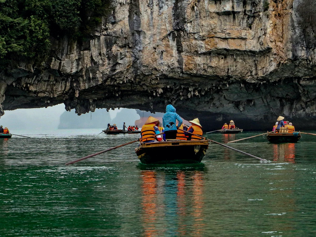 A group of kayaks head towards a cave on the water