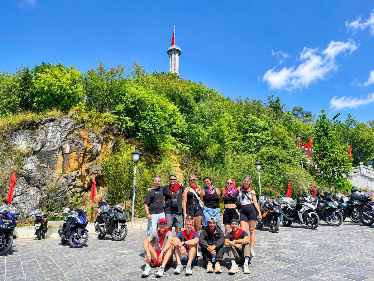 A group of people pose in front of a tower that stretches into the sky