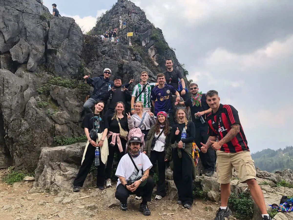 Group of people pose in front of a jagged rock formation