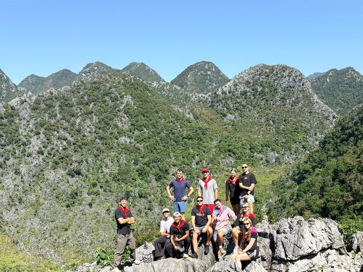 A group of people stand with mountains behind them