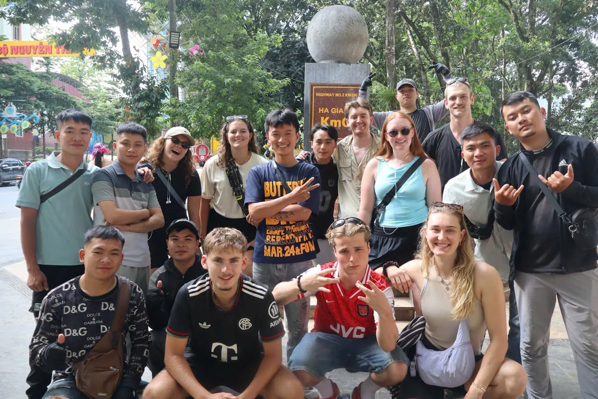A group of people pose in front of a pillar that says KM0