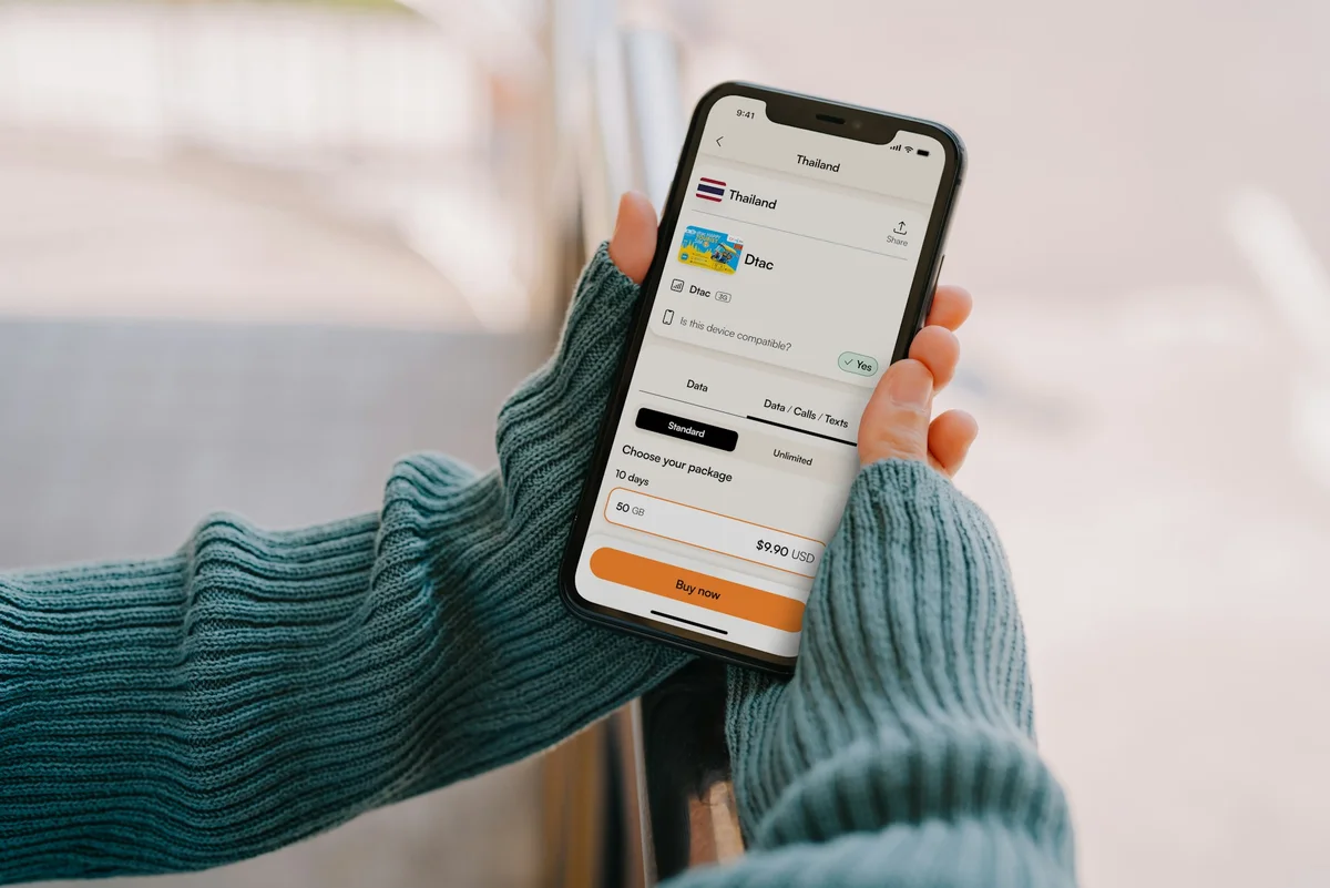 A hand holds a phone up with an eSIM app open on the phone