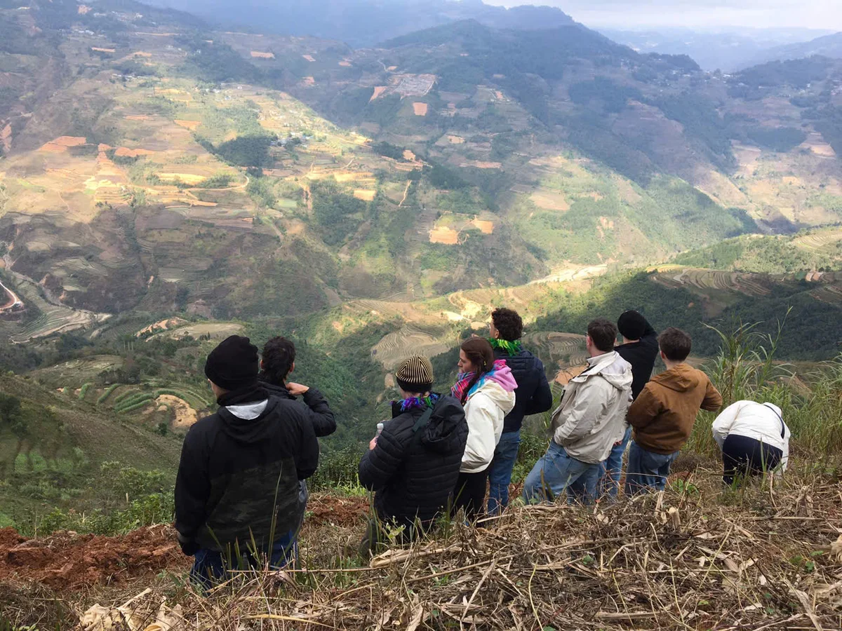 A group of people admire the view of mountains in the sunshine with their backs to the camera
